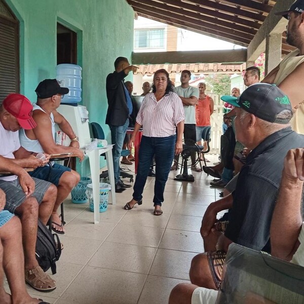 Grupo de pessoas em varanda, mulher em pé no centro.
